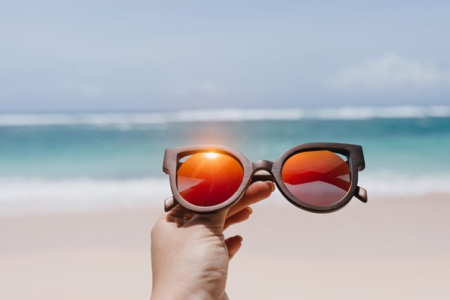 Main tenant des lunettes de soleil sur une plage